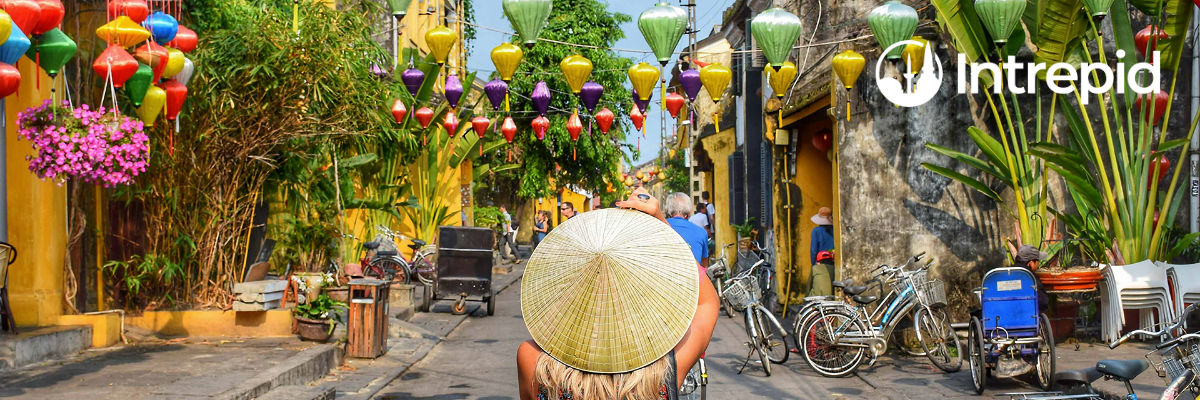 woman with straw rice picking hat looks at the colourful streets of vietnam
